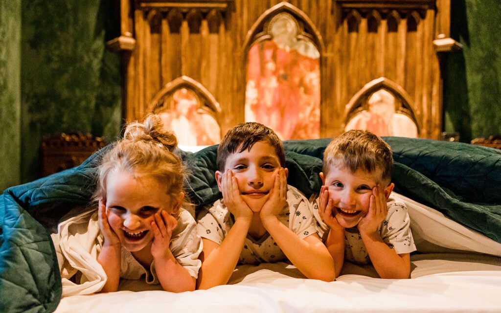 Children relaxing together on a bed inside a woodland bothy
