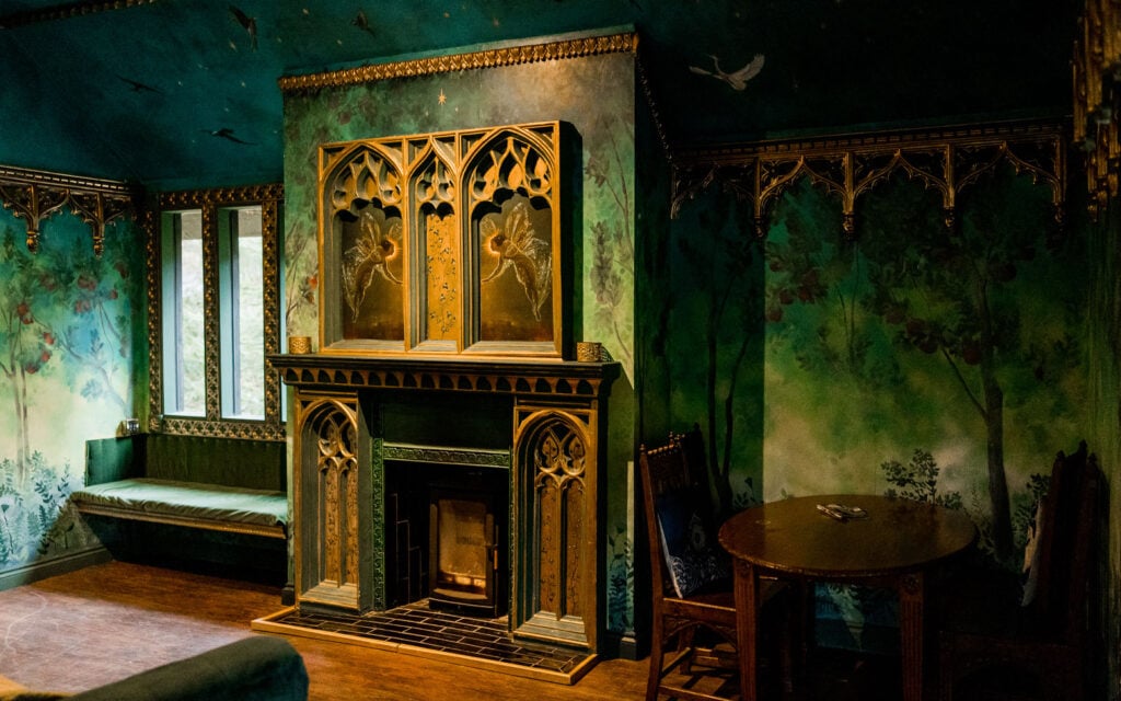 Fairytale fireplace and painted woodland interior inside Dreamery Hideaway bothy