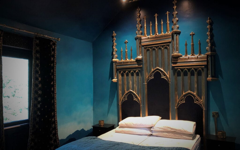 Moody woodland bedroom with ornate headboard at The Dreamery Hideaway
