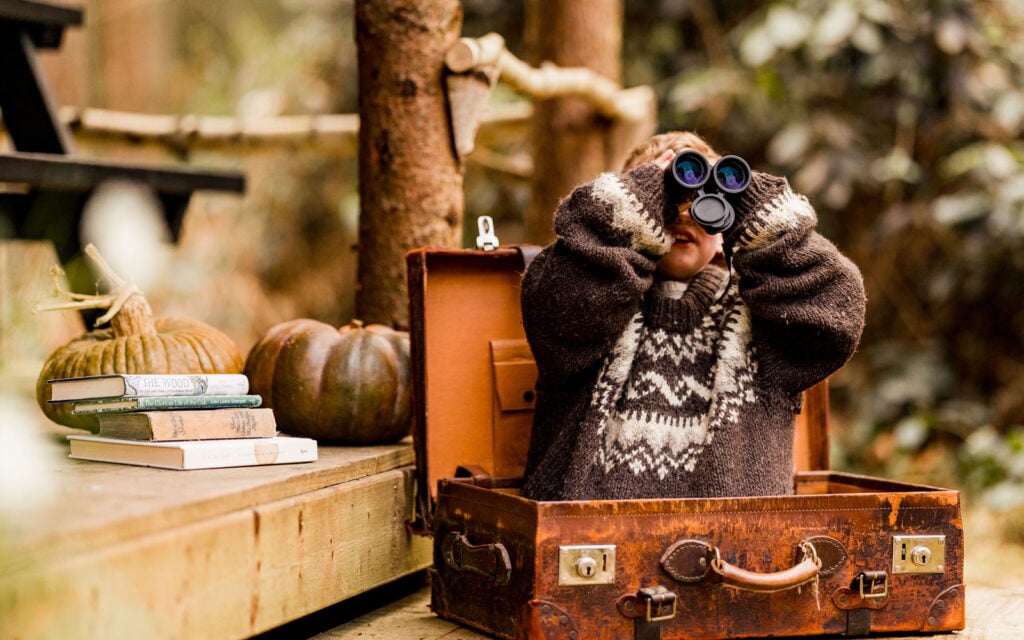 Child exploring the woodland with binoculars at The Dreamery Hideaway